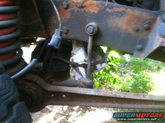 Close-up of rusty vehicle frame with suspension components and a tire visible