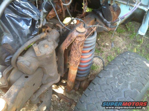 Close-up of a rusty front suspension system and tire on a vehicle
