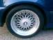 1991 BMW 3 Series - Close-up of a blue BMW's wheel, a classic BBS-style design and the BMW emblem, consistent with a 1991 3 Series.