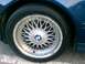 1991 BMW 3 Series - Close-up of a blue car's wheel, a BMW emblem and a multi-spoke rim with visible damage.