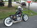 1972 Ford Ranchero - Custom motorcycle parked on asphalt with grass and trees in the background.
