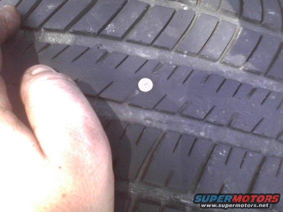 Close-up of a tire tread with a nail embedded