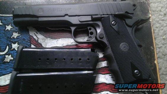 Black Taurus pistol with two magazines on a surface with an American flag design