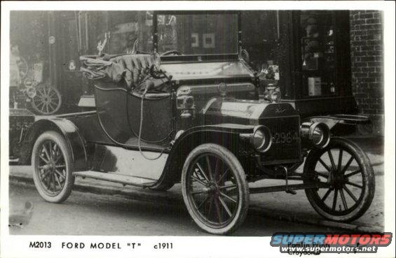 Ford Model T touring car with a soft top, parked outside a building
