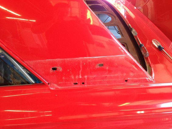 red car body panel with holes drilled for trim, two screwdrivers nearby