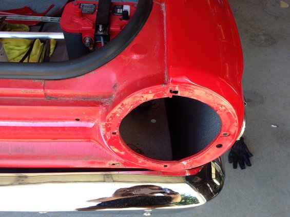 Red 1964 Ford Fairlane rear quarter panel, taillight opening visible, chrome bumper below, battery in trunk area