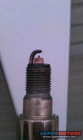 Close-up of a used spark plug with visible wear on the electrode