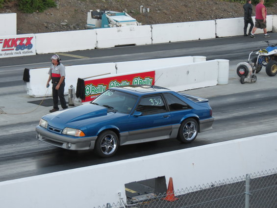 Blue 1990 Ford Mustang on a drag strip with racing numbers on the window