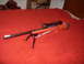 1990 Max II - Rifle with scope and bipod resting on a red blanket.