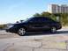 2003 Ford Taurus - A black 2003 Ford Taurus sedan is parked on a cracked asphalt surface with a building and trees in the background.