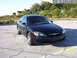 2003 Ford Taurus - A black 2003 Ford Taurus is parked in a lot with a body of water and buildings in the background.