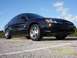 2003 Ford Taurus - A black 2003 Ford Taurus sedan is parked on a paved surface under a blue sky with scattered clouds.
