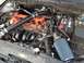 1987 Ford Bronco - The engine bay features aftermarket modifications including an upgraded air intake system and orange painted valve covers.