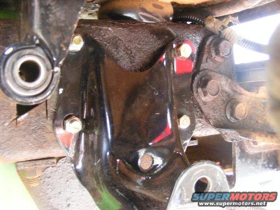 Close-up of a black metal bracket with bolts, part of a vehicle's suspension system