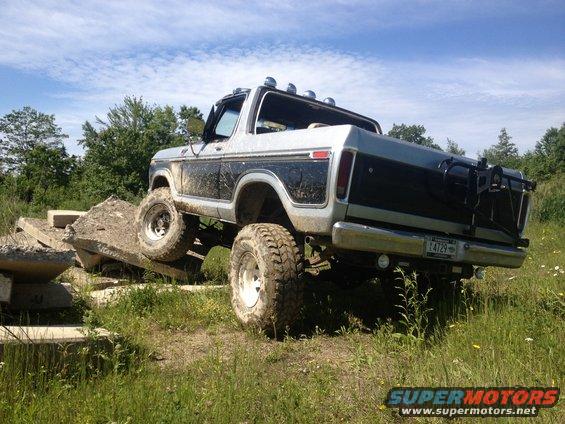 Lifted Ford Bronco with mud on it, driving over concrete obstacles. License plate L4729