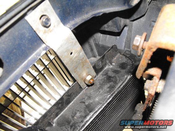 dscf2584.jpg This must be the 6th or 7th time I've mounted a trans cooler on an M-body and I'm getting better at it each time. I pride myself in not drilling or self tapping anything on. Instead I use existing bolts on the body to hold the strap steel and sheet metal brackets to the car. This is the top passenger's side of the cooler being secured by backing out and re-tightening a rear grill support bolt.