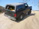 1988 Ford Bronco - 1988 Ford Bronco driving off-road, spare tire visible in the cargo area.