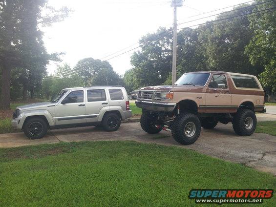 Brown and tan lifted Ford Bronco with large tires, parked next to a silver SUV