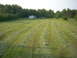 2000 Chevrolet Tahoe - A rural scene shows freshly cut grass in rows across a field, with a house and trees in the distance.