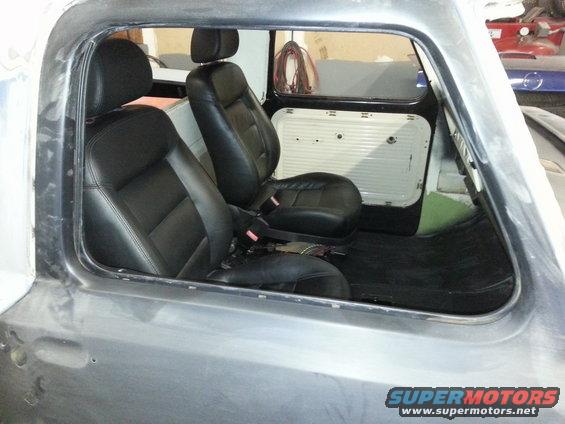 Interior of a truck cab with black bucket seats and door panels. The exterior is unfinished