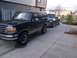 1994 Ford Bronco - Two vehicles parked in a driveway outside a modern building.