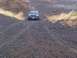 1994 Ford Bronco - A black Ford Bronco navigates a rough, rocky terrain with dry grass on the sides.