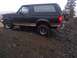 1994 Ford Bronco - A dark-colored Ford Bronco navigates a steep, rocky incline with a spare tire mounted at the back.
