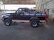 1994 Ford Bronco - Side profile of a black 1994 Ford Bronco with tan trim, parked indoors.