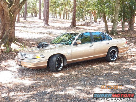 Gold 1993 Ford Crown Victoria with hood scoop and black wheels parked outdoors