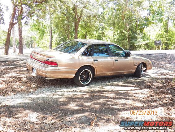 Gold 1992 Ford Crown Victoria sedan parked on gravel, trees in background