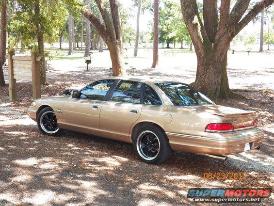 Gold 1993 Ford Crown Victoria sedan, 3q-front view, parked under trees