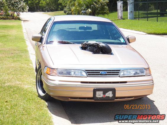 Gold 1993 Ford Crown Victoria, front view, with a supercharger on the hood and a '5.4' license plate