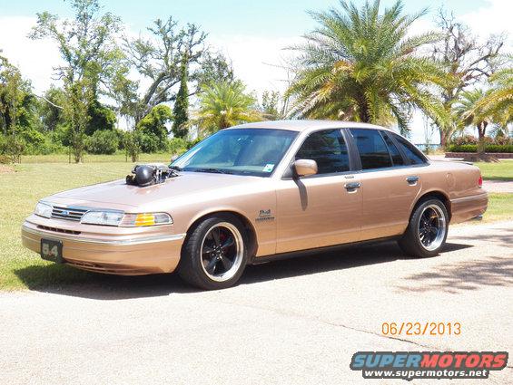 1993 Ford Crown Victoria with hood scoop and custom wheels, parked outdoors