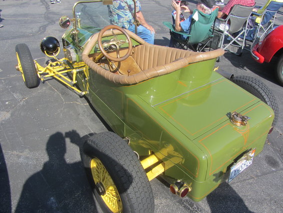 Green custom hot rod with yellow accents and tan interior, seen from the front three-quarter view