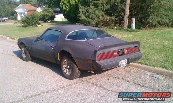 Dark coupe with a rear spoiler and horizontal taillights parked curbside