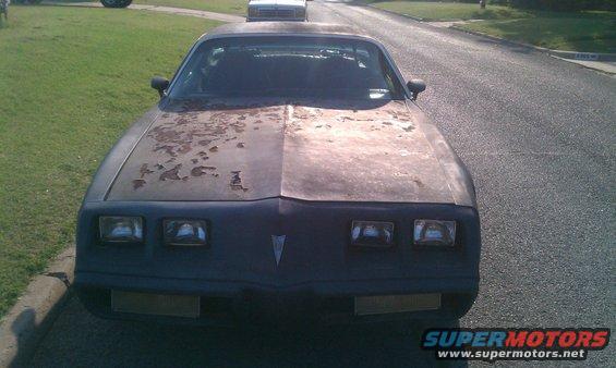 Front view of a rusty 1979 Pontiac Firebird with peeling paint