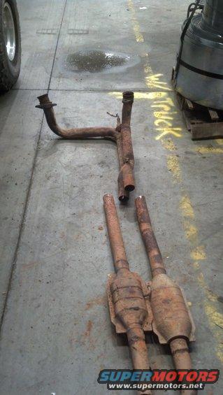 Rusty exhaust pipes and two catalytic converters on a concrete floor