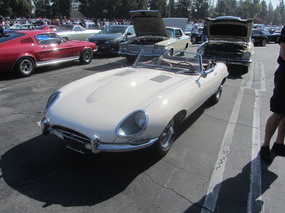 Cream-colored convertible sports car with chrome accents and wire wheels, parked on asphalt