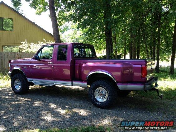 Purple 1992 Ford F-150 pickup truck with chrome trim and large tires, parked on gravel