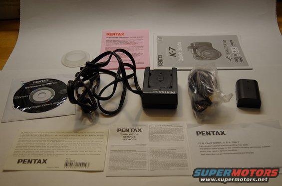 Pentax K-7 camera accessories including a CD, battery charger, battery, and manuals