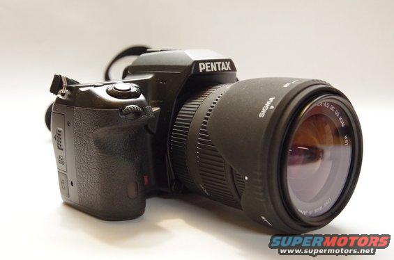 Pentax DSLR camera body with a Sigma zoom lens attached. Text on lens reads 'SIGMA 18-50 DC OS HSM'