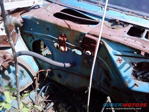Rusted blue car engine bay with a grey hose and visible wiring