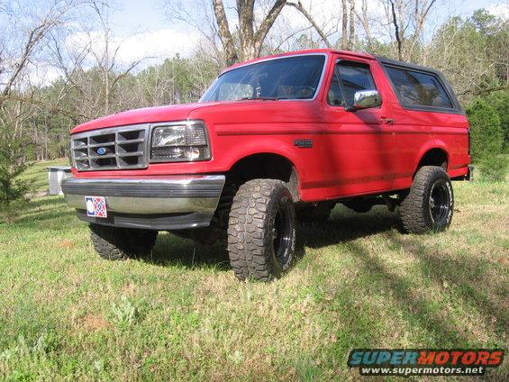Red 1992 Ford Bronco parked on grass with trees in the background