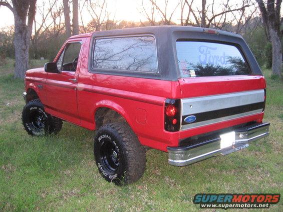 Red 1992 Ford Bronco 3/4 front view with black top and lifted suspension