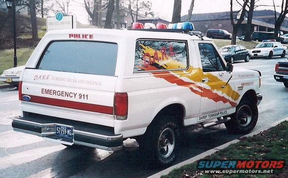 1992 Ford Bronco police SUV, rear 3/4 view, white with D.A.R.E. graphics