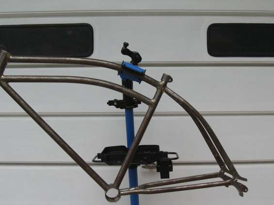 Bare bicycle frame on a stand against a white paneled background
