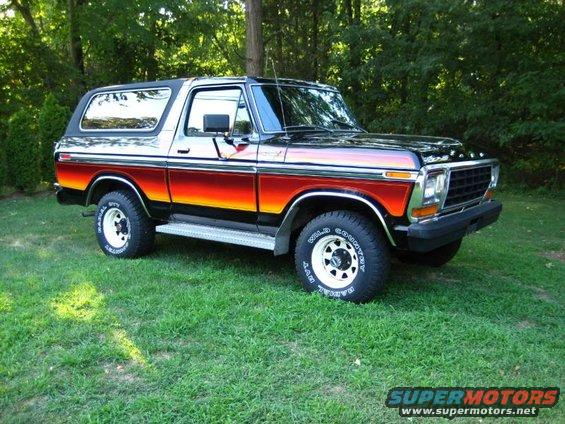 1978 Ford Bronco with sunset paint, 3q-front view. Tires read 'Wild Country'