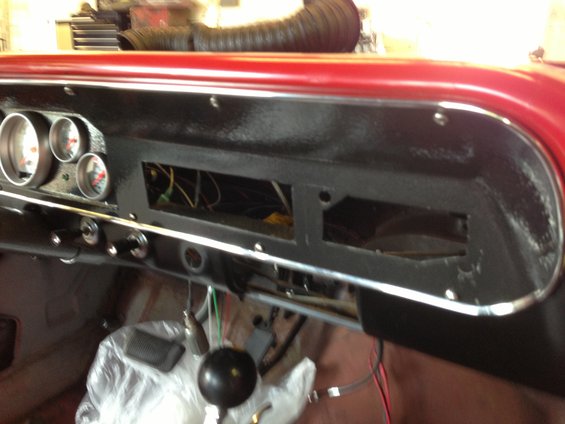 Car dashboard showing aftermarket gauges, exposed wiring, and a gear shifter