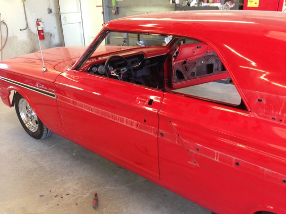 Red coupe with doors off, showing interior gauges and unfinished body panels. Fairlane script visible on fender