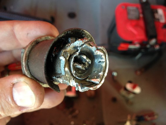 Hand holding a damaged cylindrical metal part with a broken interior mechanism